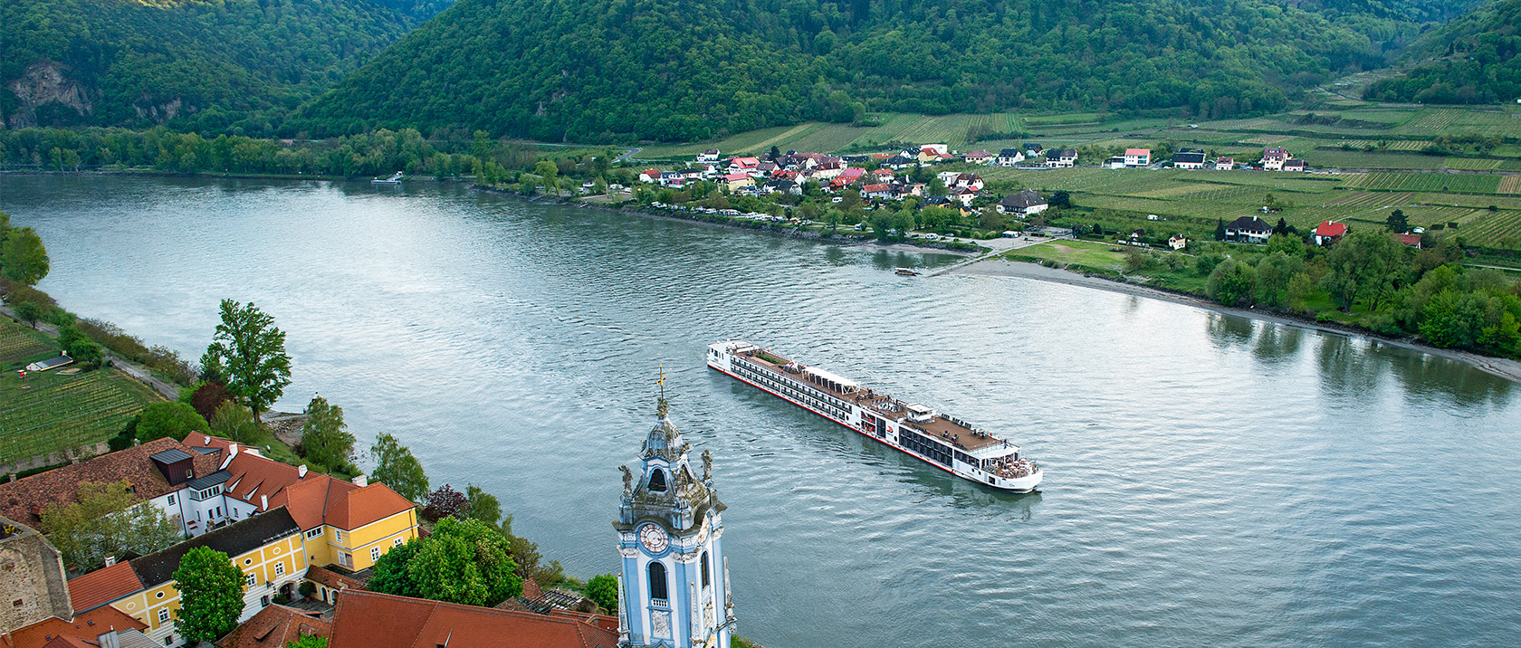Aerial view of a Viking river ship sailing past Dürnstein, Austria along the Danube river