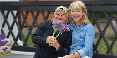 Karine Hagen and Nadya, a grandmotherly woman holding boquets of purple flowers.
