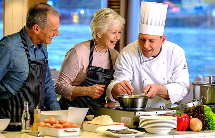 A chef teaching a cooking class to two people