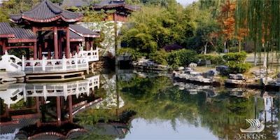 Chinese gardens and buildings over a small, tranquil pond.